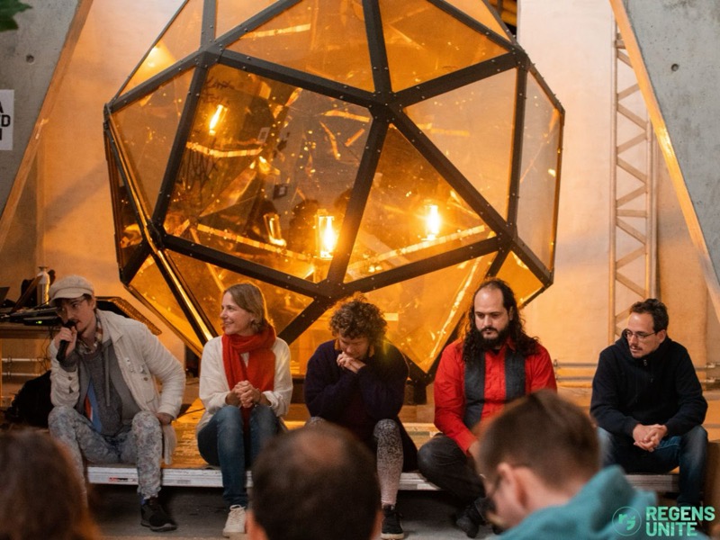People sitting and talking in front of a large glowing geodesic dome at Moos, Berlin