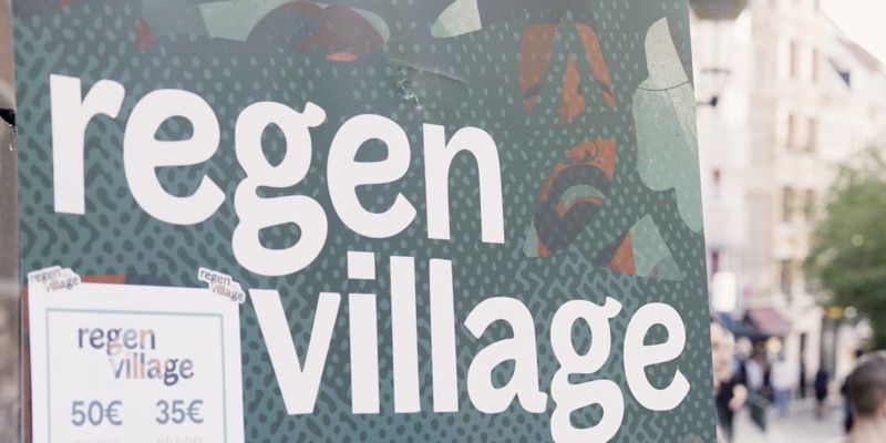 The green Regen Village sign on a Brussels street during EthCC
